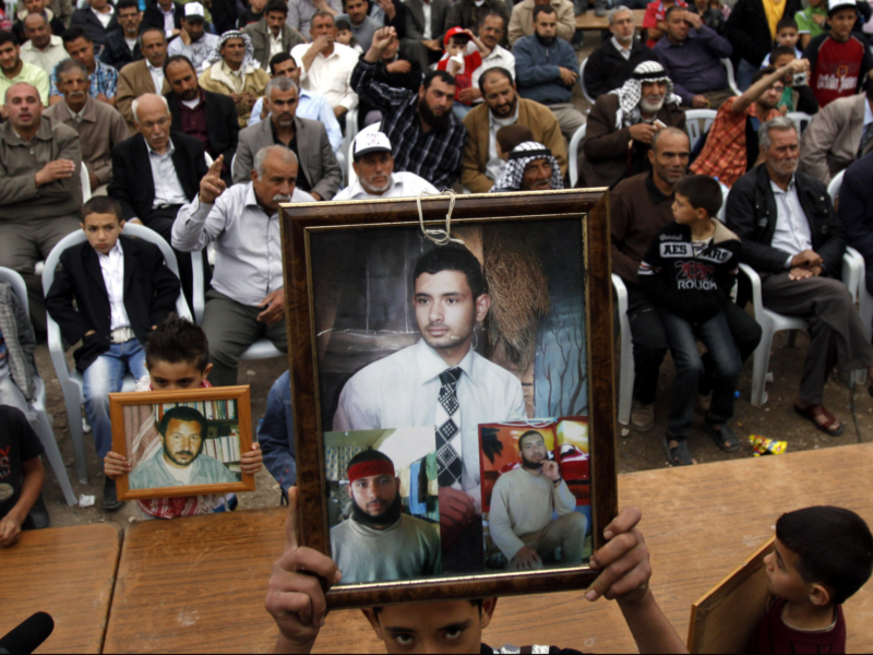Palestinians hold photographs of prisoners jailed in Israel during a celebration for the liberation of Palestinian Khader Adnan in the West Bank village of Arrabeh, near Jenin, Wednesday, April 18, 2012. The same week, hundreds of Palestinian prisoners held by Israel launched a hunger strike the protesting their conditions and demanding an end to detentions without trial. (AP Photo/Mohammed Ballas)