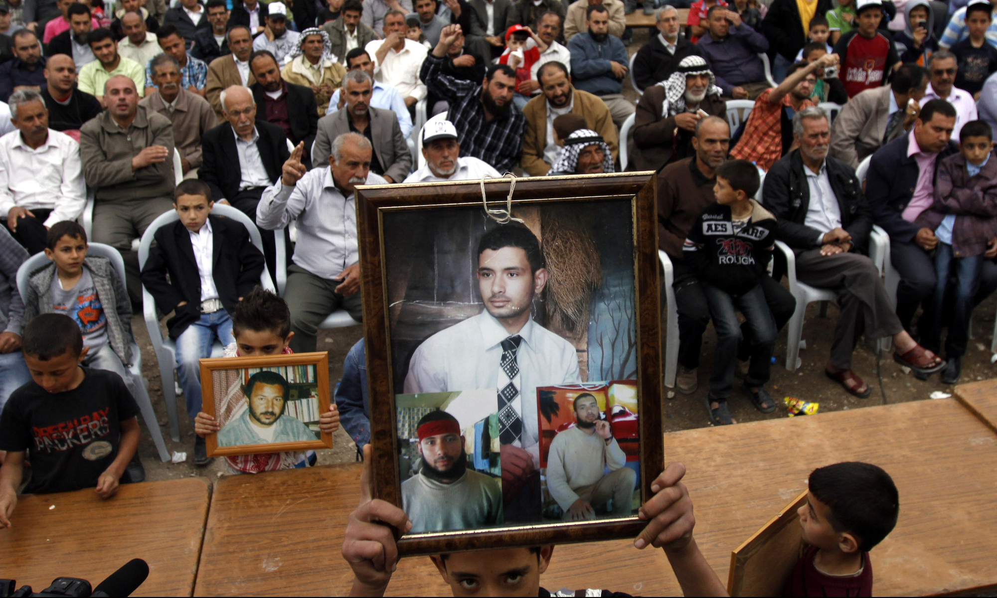 Palestinians hold photographs of prisoners jailed in Israel during a celebration for the liberation of Palestinian Khader Adnan in the West Bank village of Arrabeh, near Jenin, Wednesday, April 18, 2012. The same week, hundreds of Palestinian prisoners held by Israel launched a hunger strike the protesting their conditions and demanding an end to detentions without trial. (AP Photo/Mohammed Ballas)