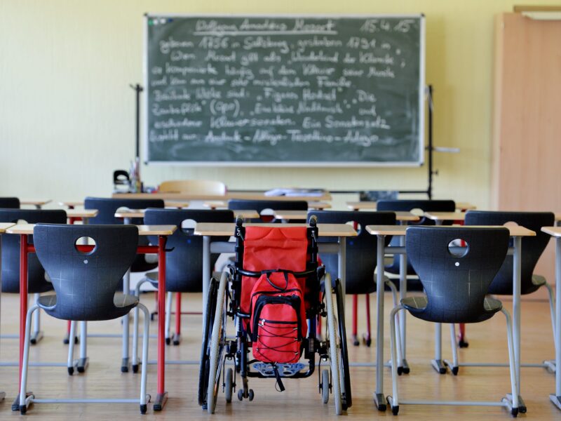 A wheelchair standing between other chairs in a school classroom. Disabled students are overlooked in the youth mental health crisis. How navigating an impossible system drove one disabled student to activism in their quest for solutions to the youth mental health crisis.