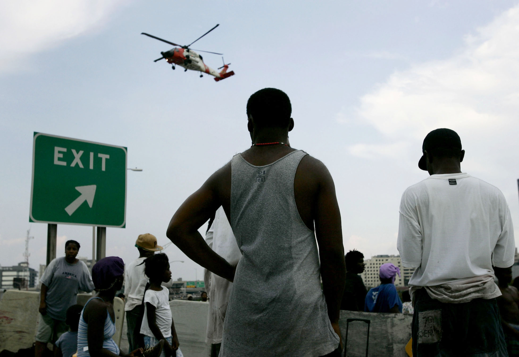 Stranded New Orleans residents watch as a helicopter evacuates others near the Superdome sports stadium August 31, 2005. Authorities have begun evacuating thousands from the damaged Superdome where living conditions have worsened since Hurricane Katrina struck on August 29, 2005. REUTERS/Jason Reed JIR/JK - RP6DRMZYNMAC Insufficient government response to the Maui wildfires follows a pattern of state abandonment forged in the aftermath of Hurricane Katrina.