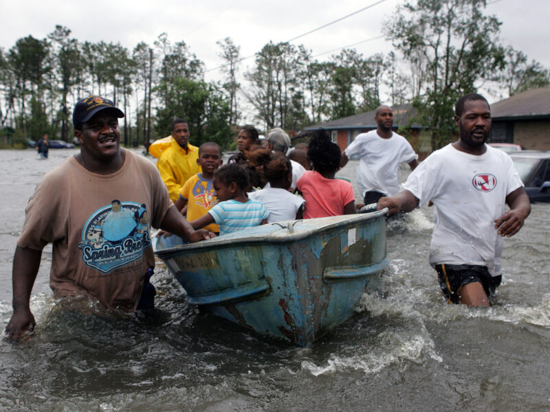 Rescuers use an old row boat to evacuate children from their flooded homes in Gulfport, Mississippi, after Hurricane Katrina struck the Gulf Coast on Monday, August 29, 2005. (AP Photo/John Bazemore) Over 18 years after Hurricane Katrina, survivors' ongoing battles with trauma, mental health, and PTSD reveal the long shadow of environmental racism on Black mental health.